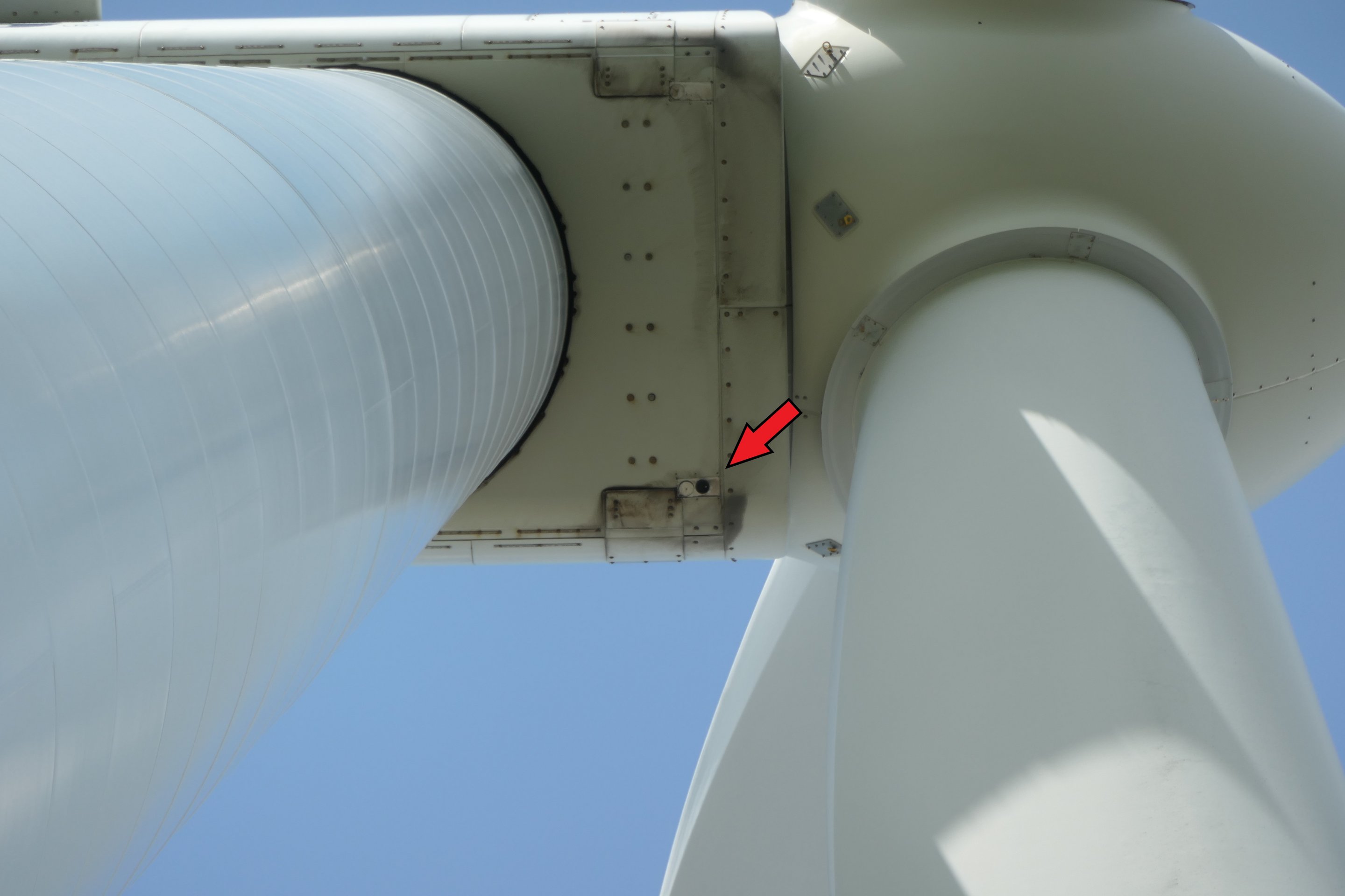 Nacelle of a wind turbine. A red arrow in the photo points to the microphone disc of the bat detection device.