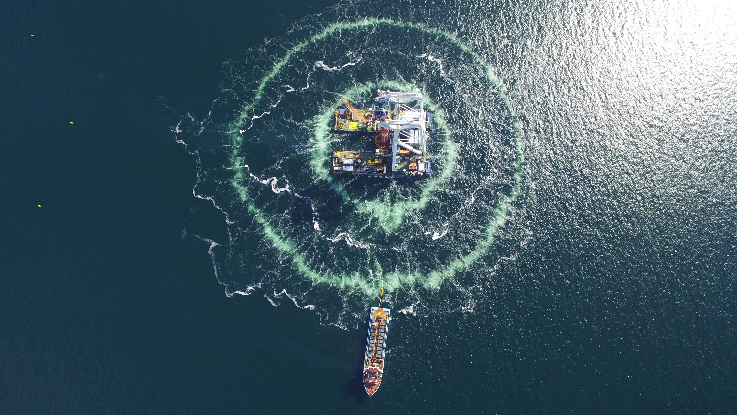 Aerial view of a piling platform for offshore wind turbines surrounded by a double bubble curtain. 
