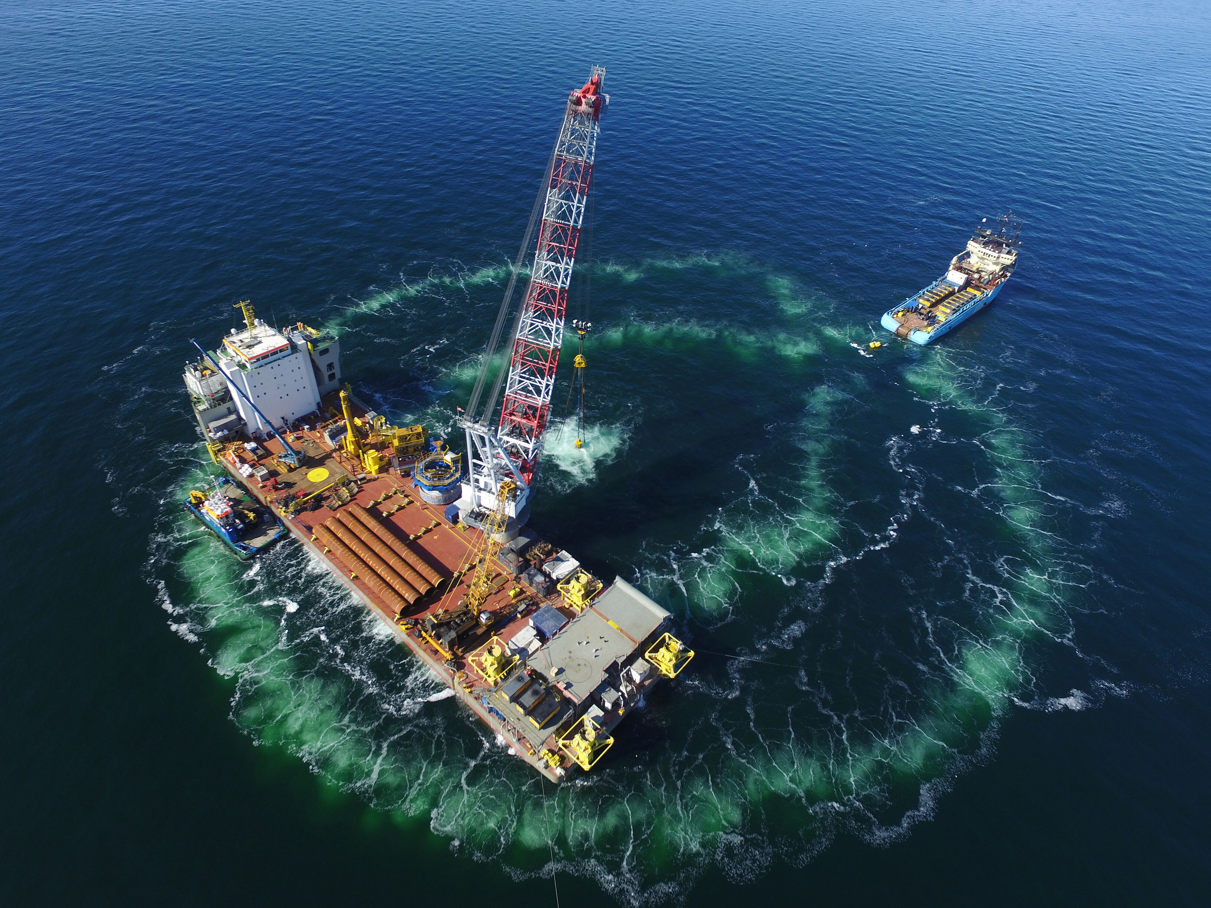 Luftaufnahme einer Rammplattform für Offshore-Windenergieanlagen, die von einem doppelten Blasenschleier umgeben wird. 