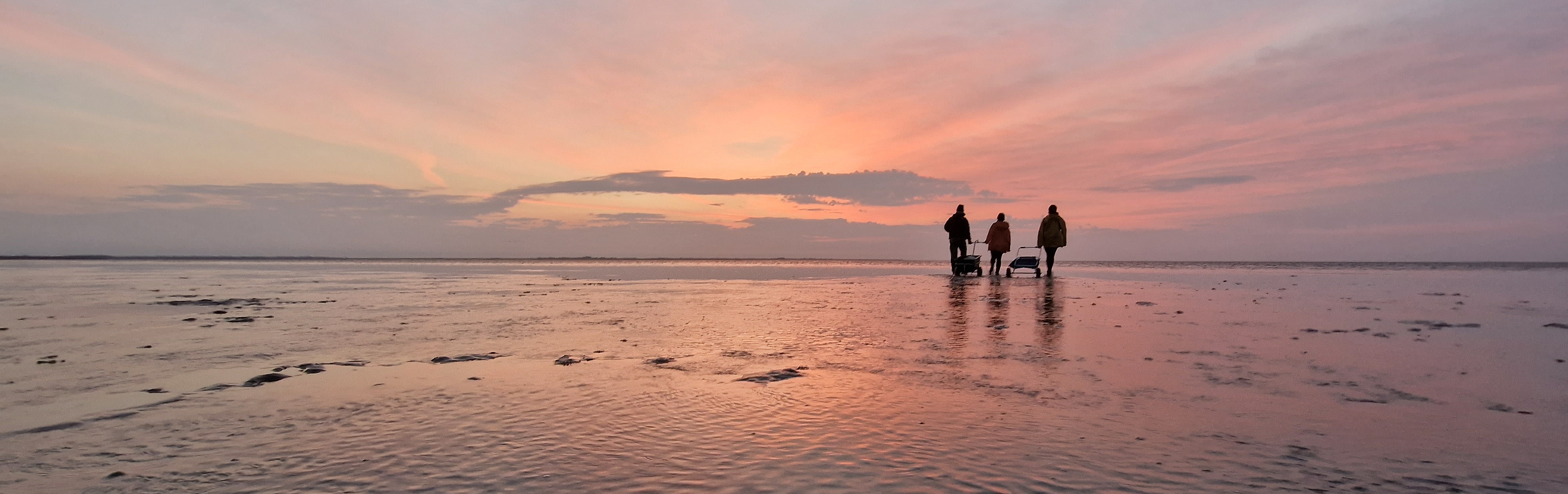 Three people at sunset in the Wadden Sea.