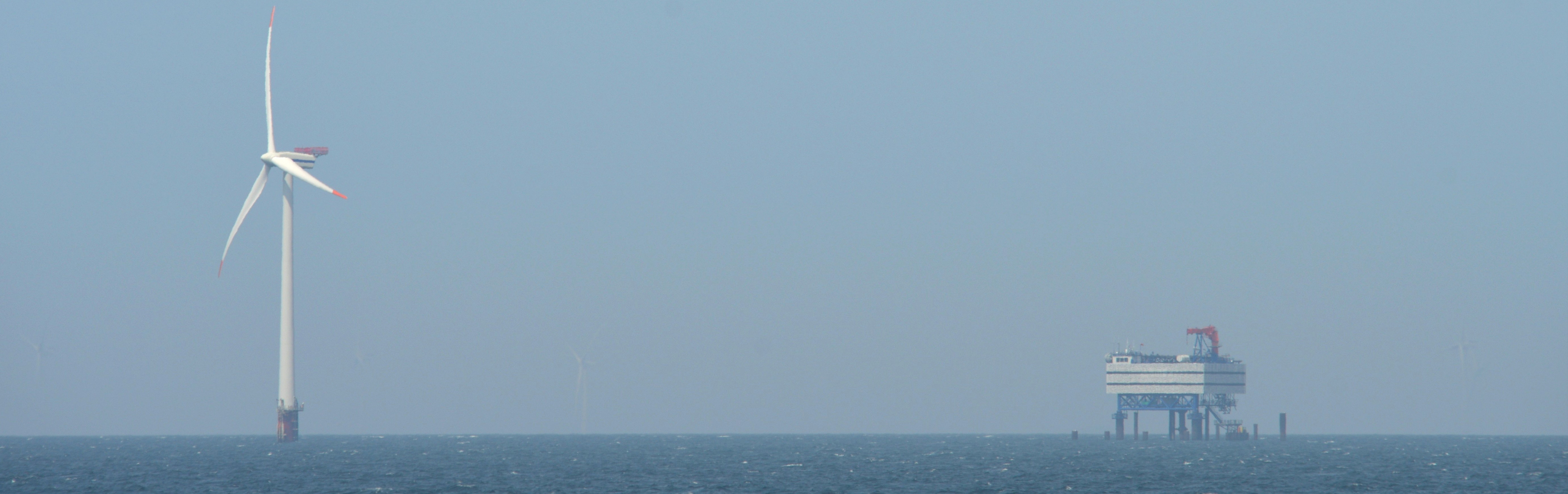 Eine Offshore-Windenergieanlage und eine Umspannplattform im Meer.